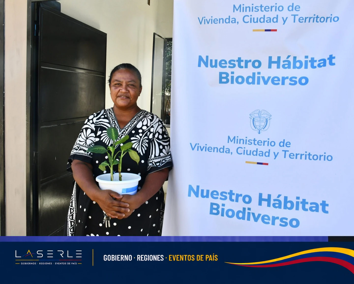 Mujer sostiene planta junto a banner gubernamental